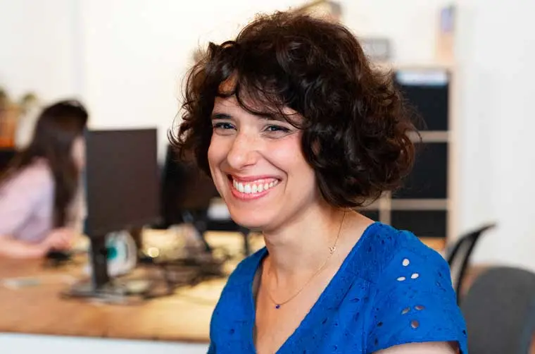 Entrepreneuse financée par l'Adie souriant à son bureau