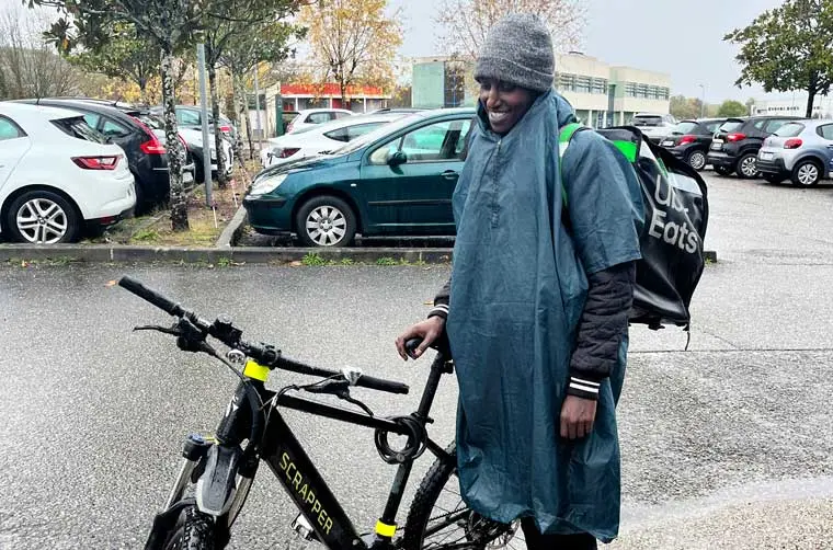 Entrepreneur livreur financé par l'Adie aux côtés de son vélo