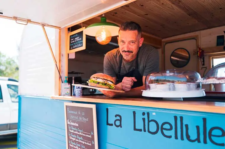 Propriétaire d'un foodtruck financé par l'Adie présentant un hamburger