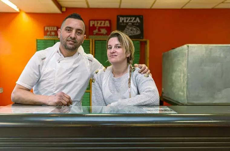 Entrepreneurs fiancés par l'Adie debout derrière le comptoir de leur camion de pizza