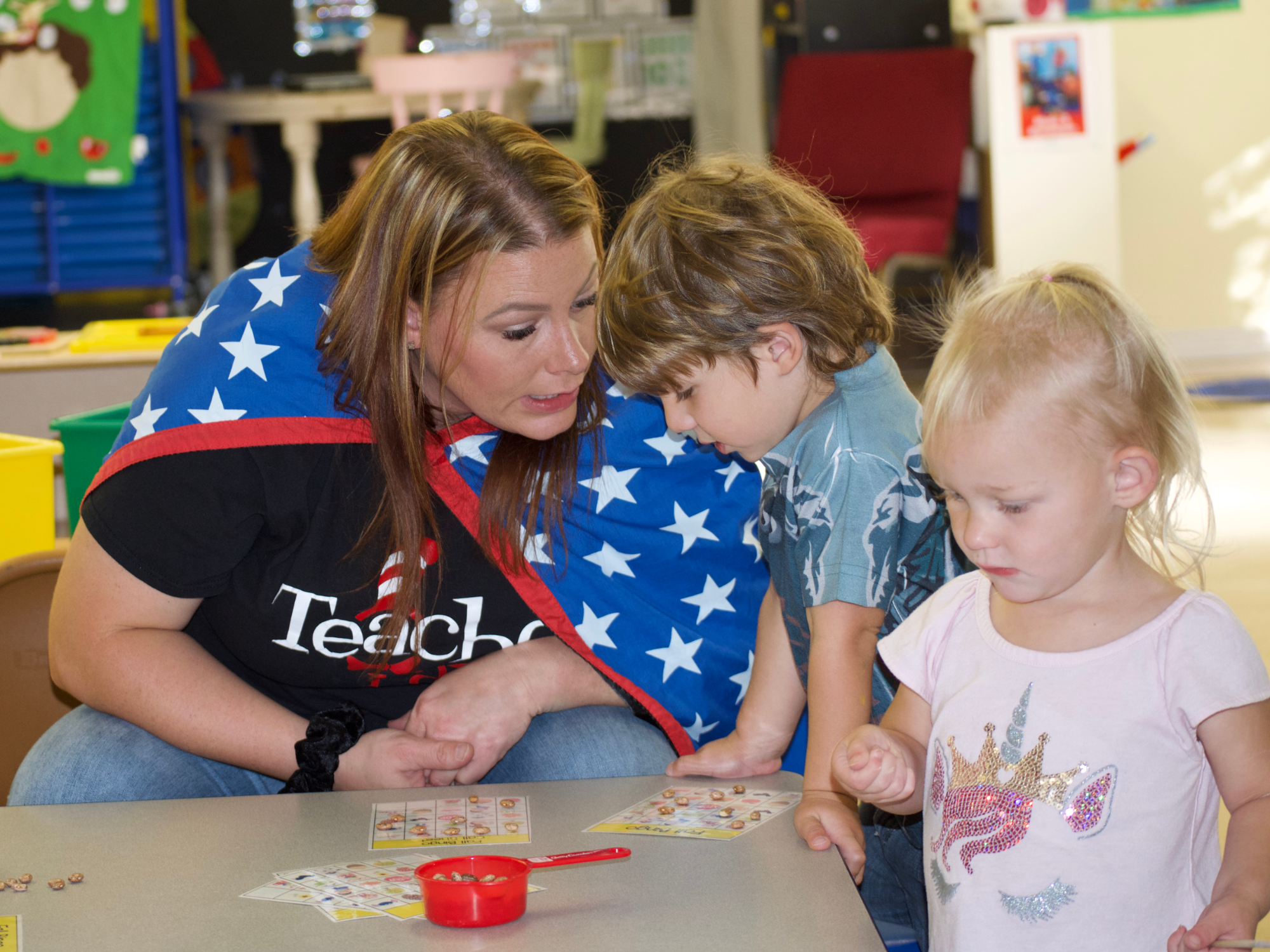 Erica Shotwell, assistant director of Little Leapers, teaches some of the children to play a fall-themed game of bingo. (Emily Tate / EdSurge)