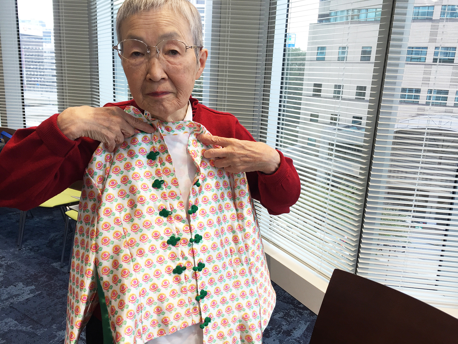Masako Wakamiya holds clothing with a flower pattern she digitally designed. (Photo Credit: Sydney Johnson)
