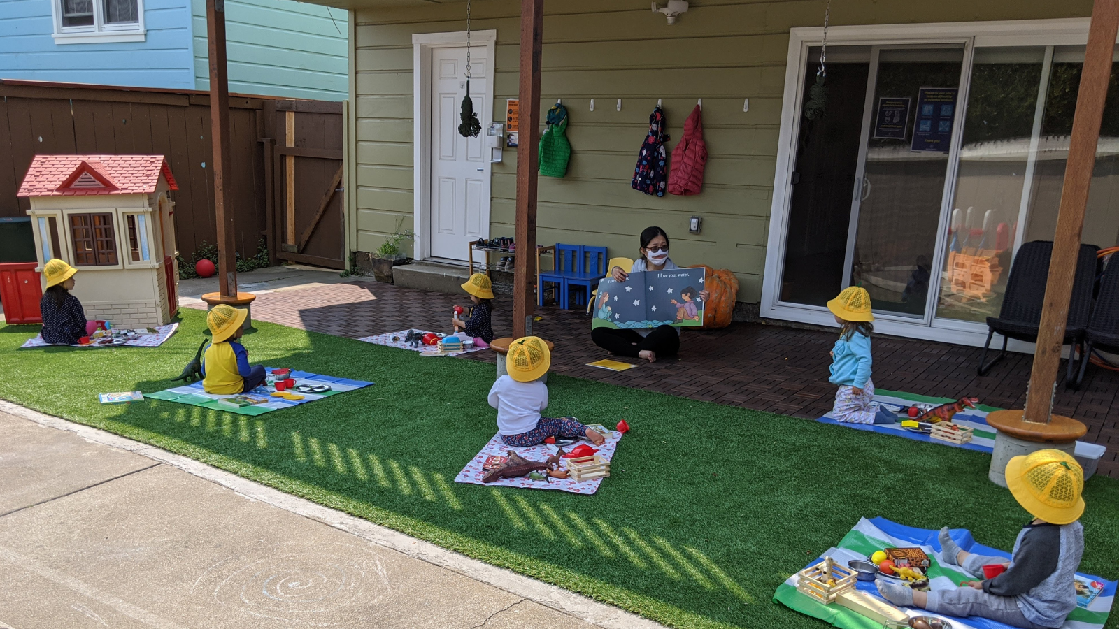 Pyrena Hui reads a story during circle time, which she started holding outside during the pandemic. Each child sits on their own blanket, six feet apart. (Photo provided by Pyrena Hui)