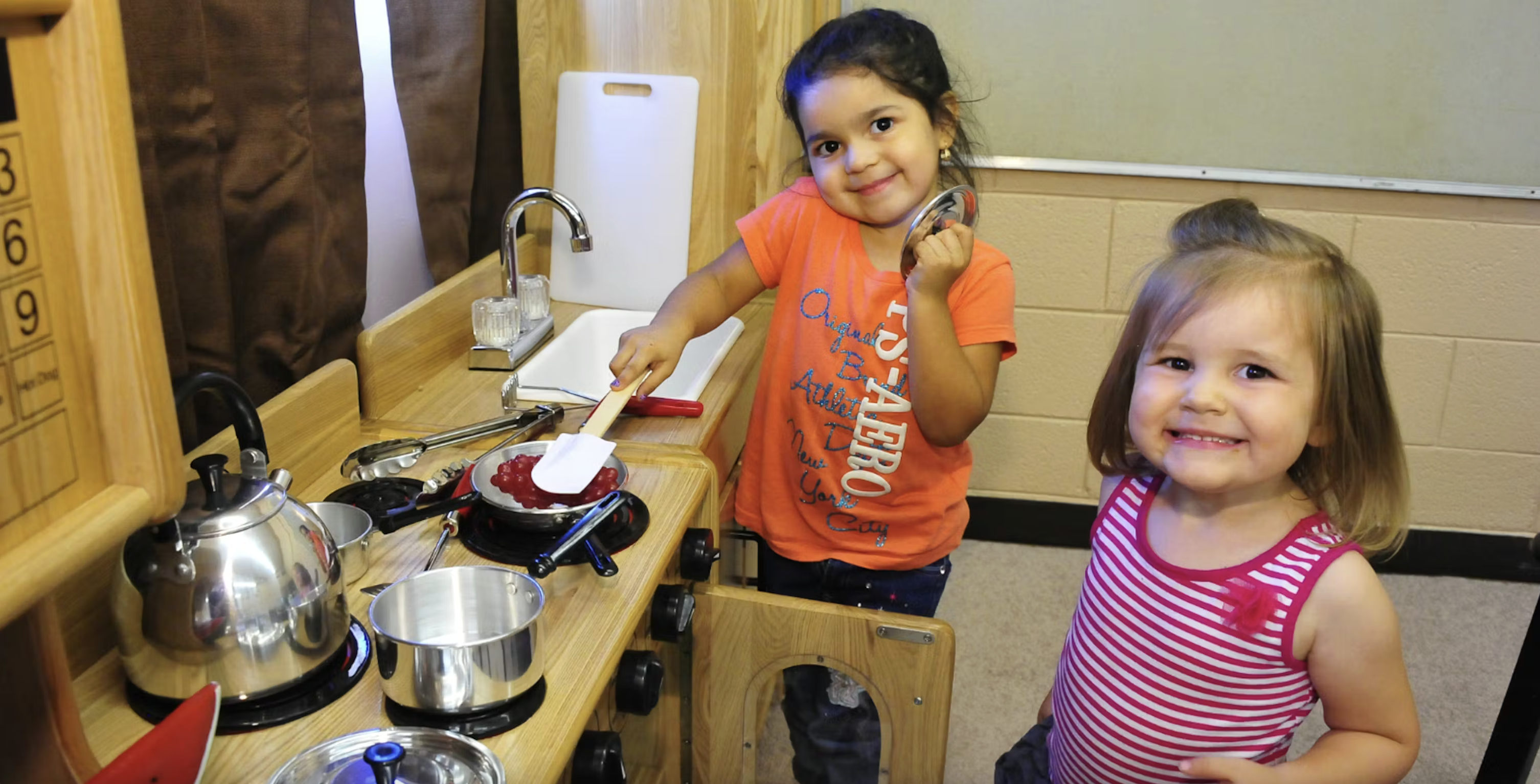Two children play in a pretend kitchen inside the Brichta Infant and Early Learning Center, a converted former elementary school in Tucson Unified School District. Photo courtesy of Tucson Unified School District.