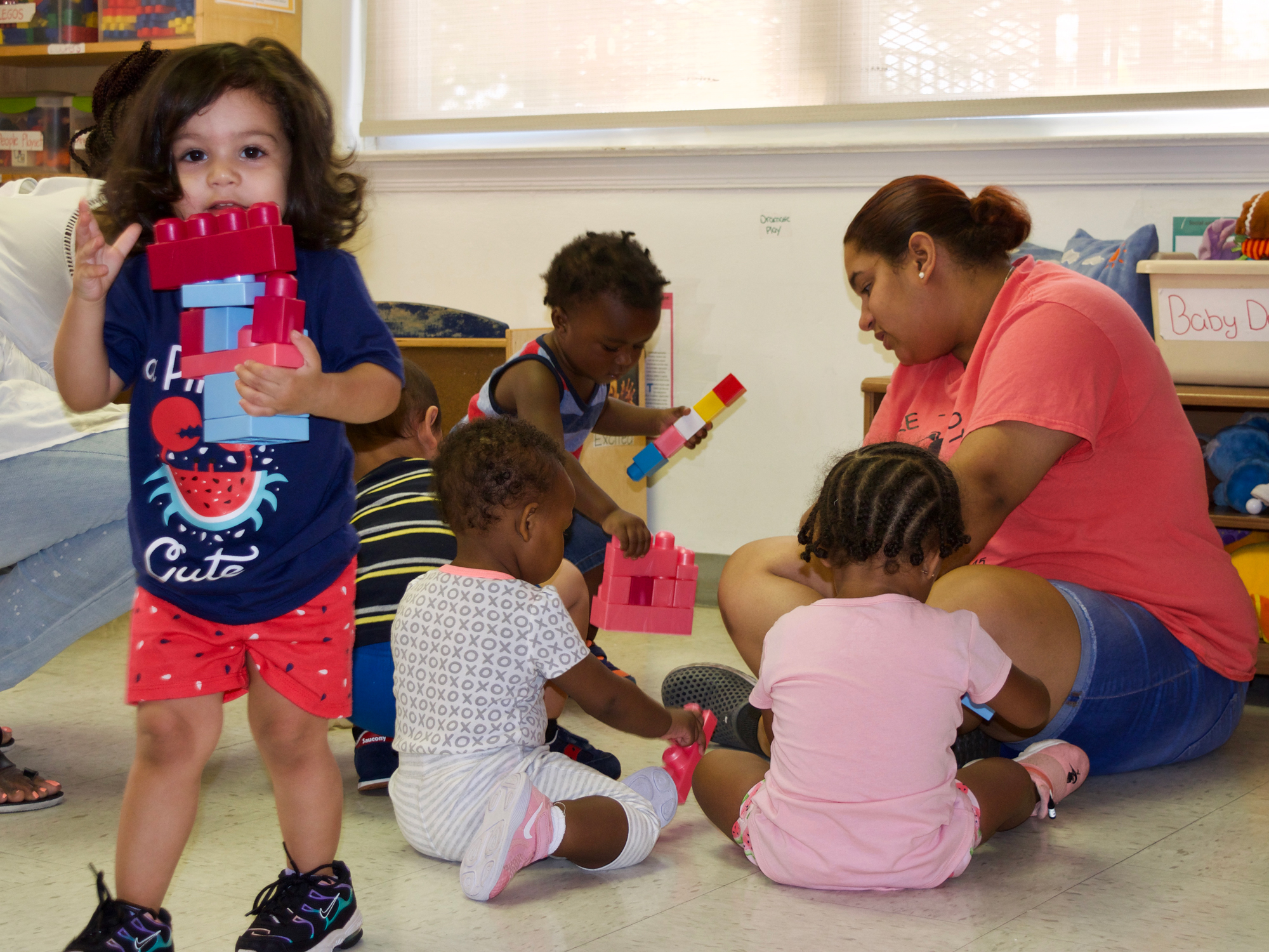 Yaribel Mercedes-Perez, an assistant teacher at Care-A-Lot, works with children in the early learning center's toddler classroom. (Emily Tate / EdSurge)