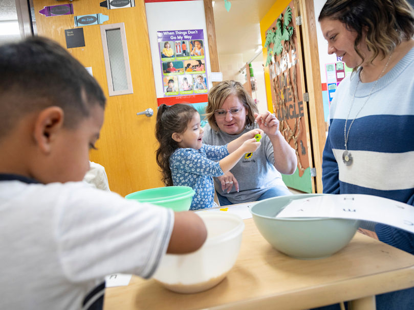 Owner Jodi Kay, center, and Director Cierra O'Brien, right, engage with students Adriel Zermeno and Harley Cadena during a literacy activity at the Sunshine City Learning Center. Photo by Kyle Green for The Associated Press.