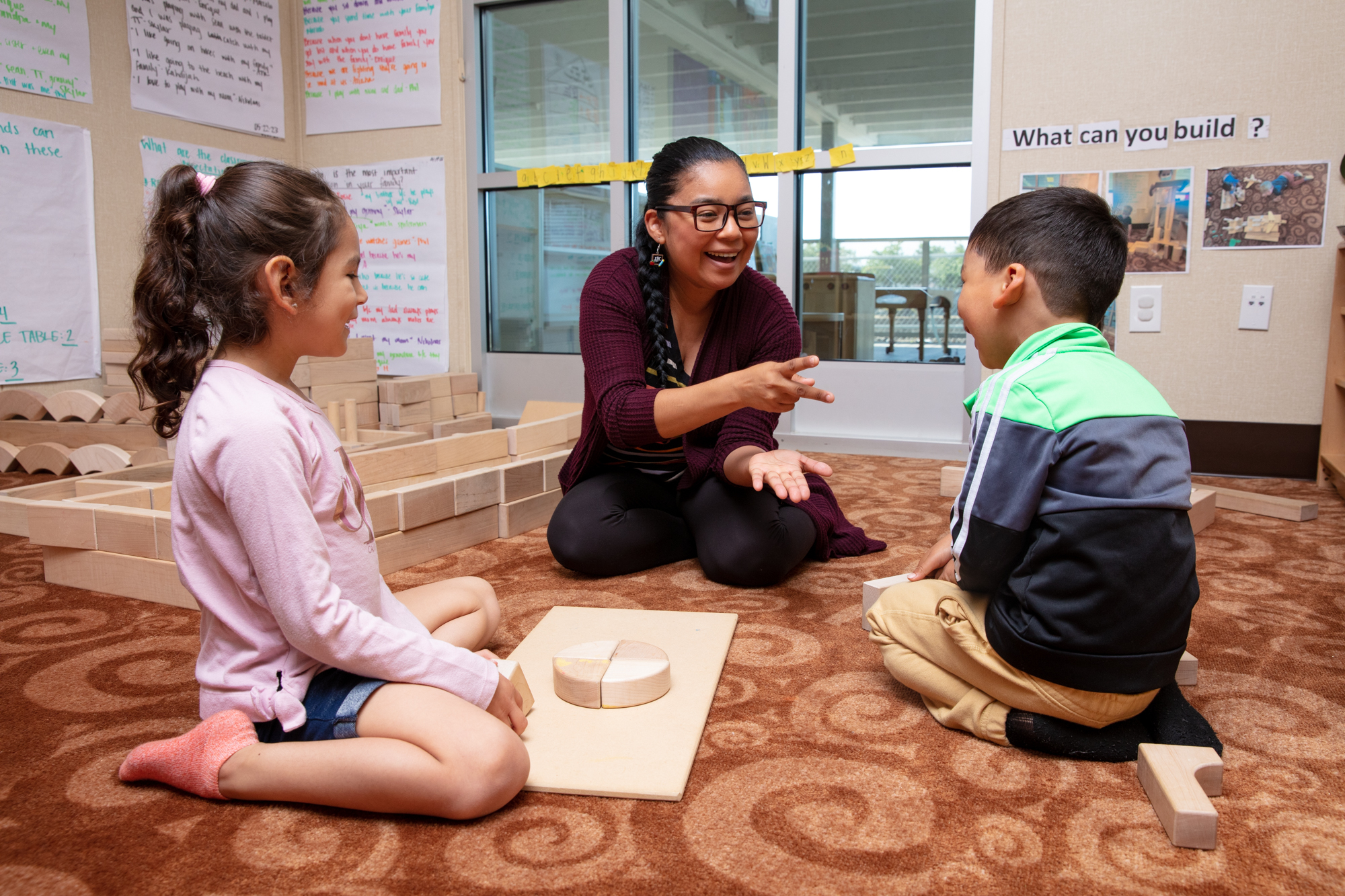 Yadira Mederos De Cardenas, center, plays games with her son, Nicolas, right, and fellow student, in her classroom at the early learning center, All Five in the Belle Haven neighborhood, in Menlo Park on June 8, 2023. Photo by Lizzy Myers for The Almanac.
