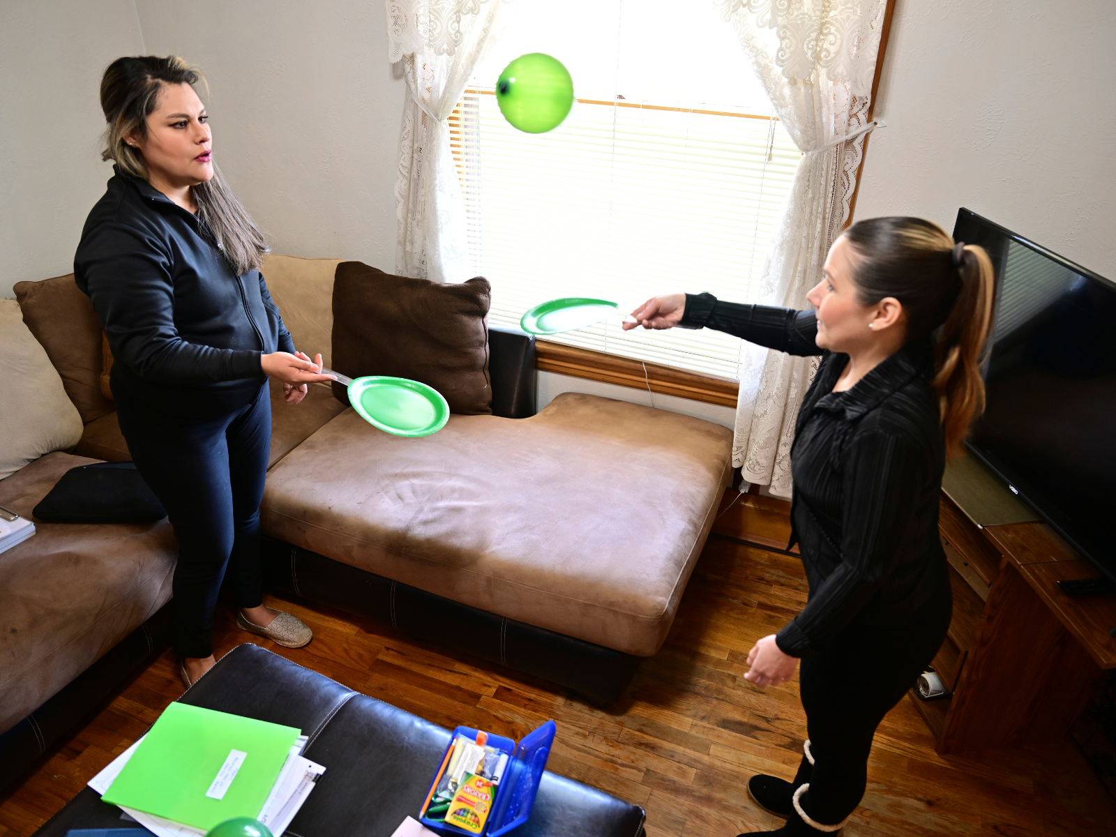 Home visitor Mayra Ocampo, left, and parent Isabel Valencia practice social and motor skills during a makeshift game of tennis. Photo by Eric Lars Bakke for AP.