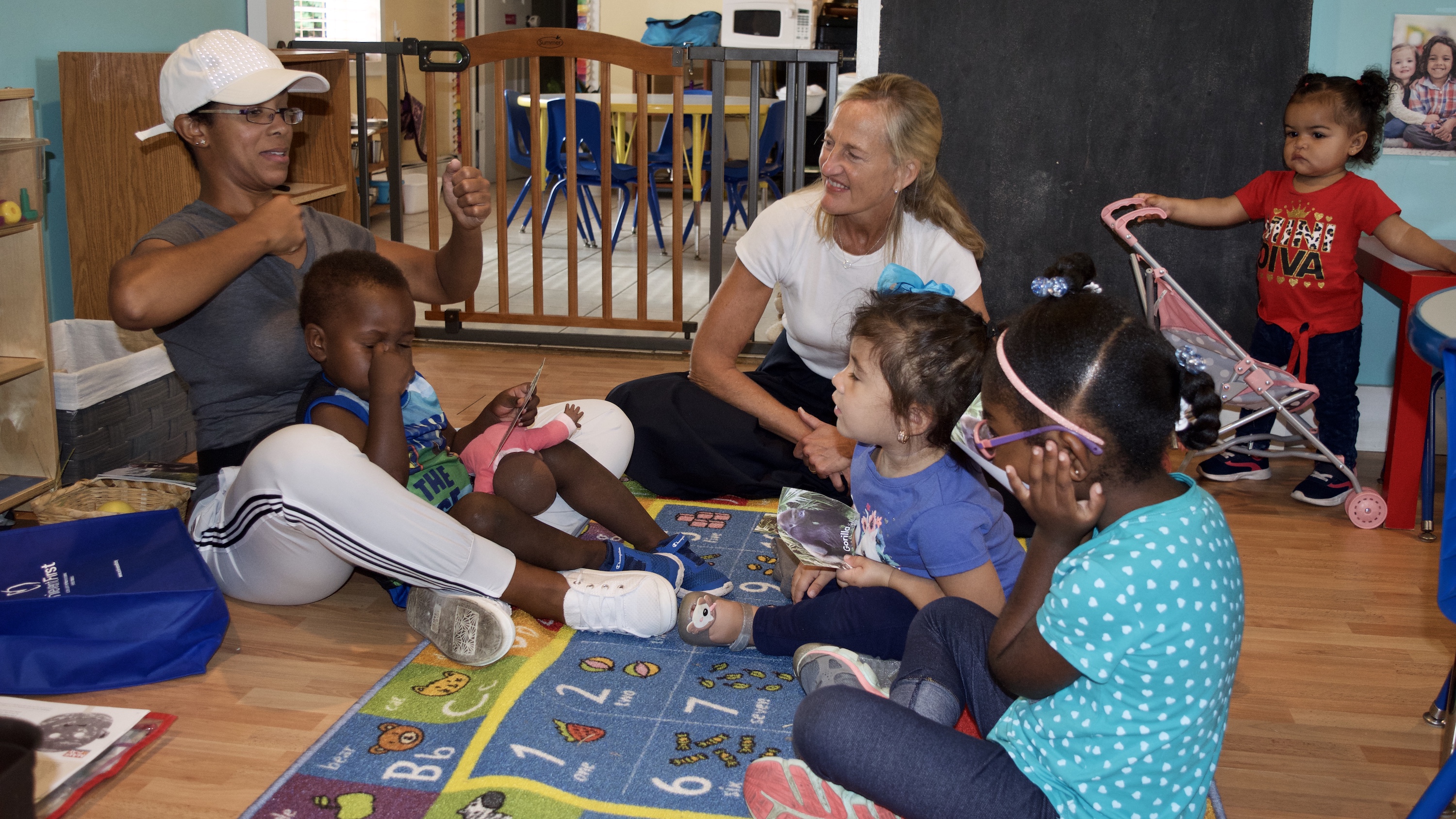 Pauline Robinson-Brown, left, imitates how gorillas beat their chests during a lesson on the mammal and the letter “g" at her family child care program. (Emily Tate)