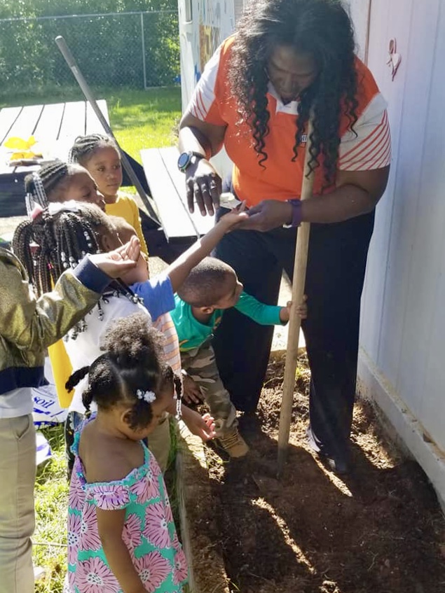 Tracy Weston, co-founder of Noah's Ark, helps children in the program plant flowers outside. (Provided by Weston)