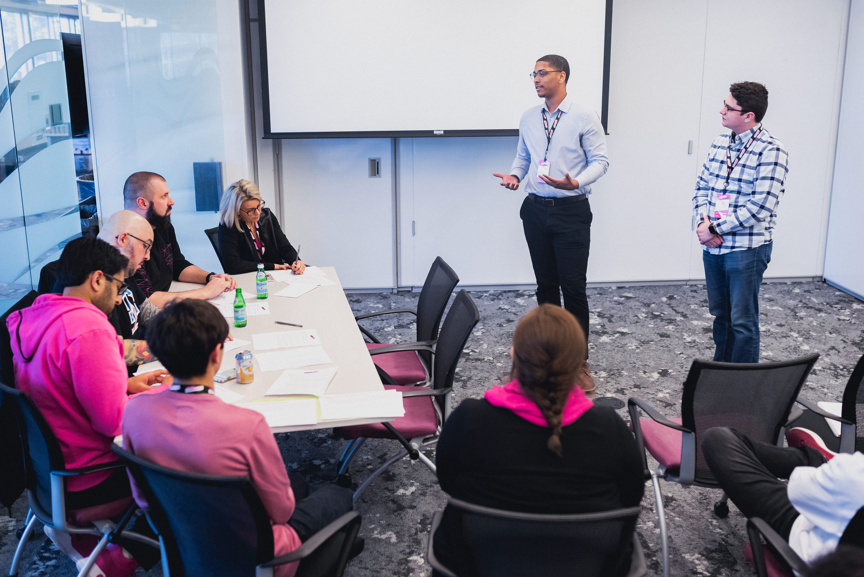 Anthony Price (standing, left) and Jesse Ferguson (standing, right) participate in a mentorship session pitching their program to T-Mobile leaders.