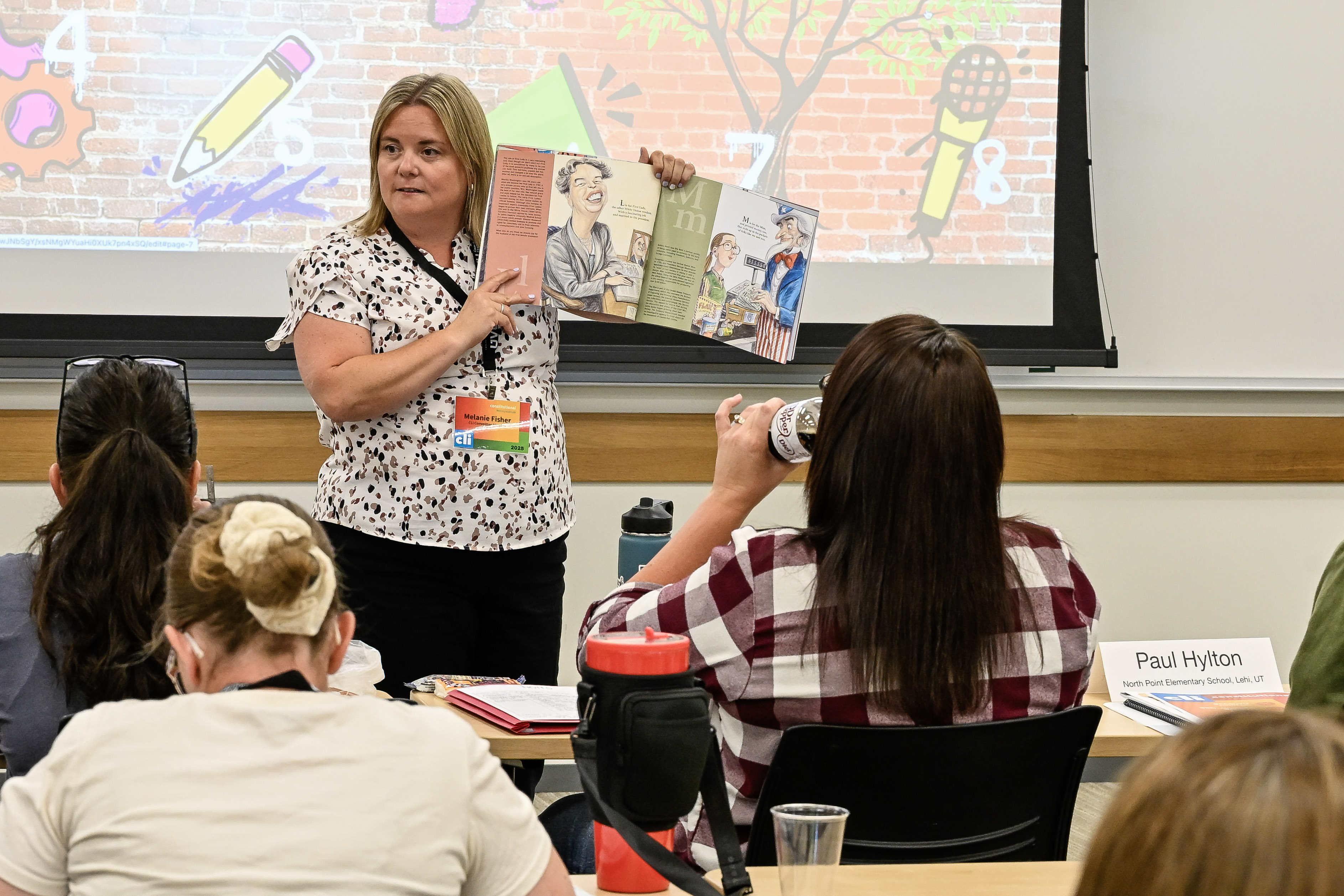 Fifth-grade teacher Melanie Fisher shows a picture book featuring American historical figures. Photo by Hank McIntire, Center for Constitutional Studies, Utah Valley University.