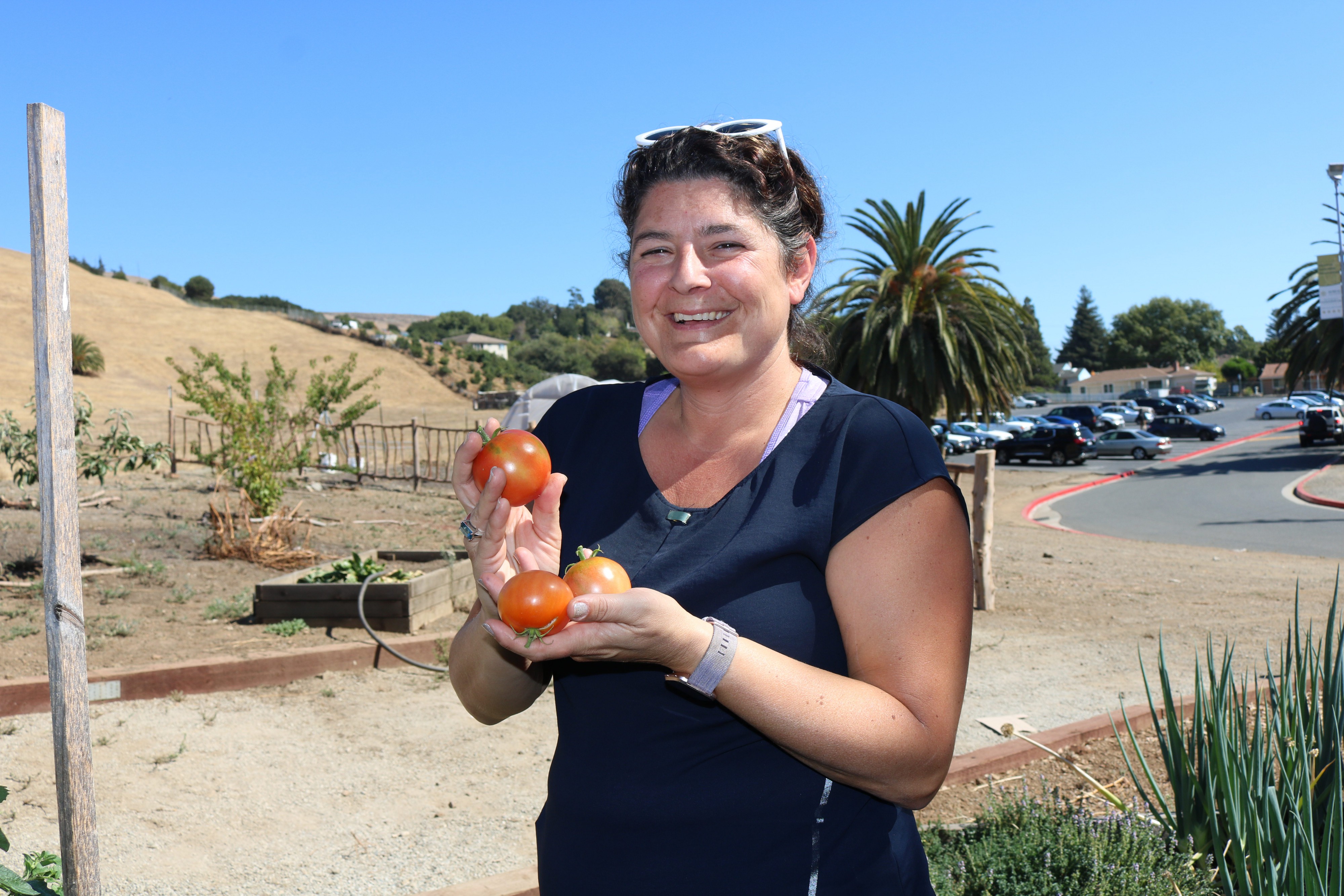 Teacher Serena Maniscalco holds tomatoes in the garden. Photo Credit: Tina Nazerian