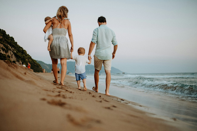 A couple walking on the beach with their children.