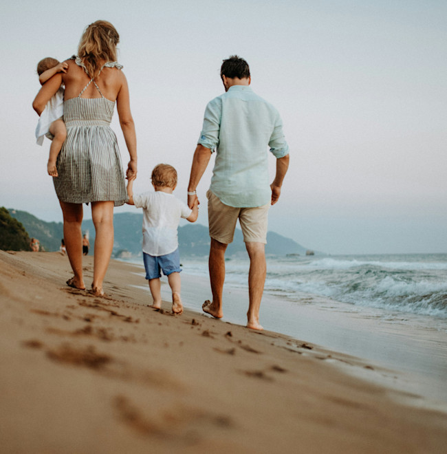 A couple walking on the beach with their children.