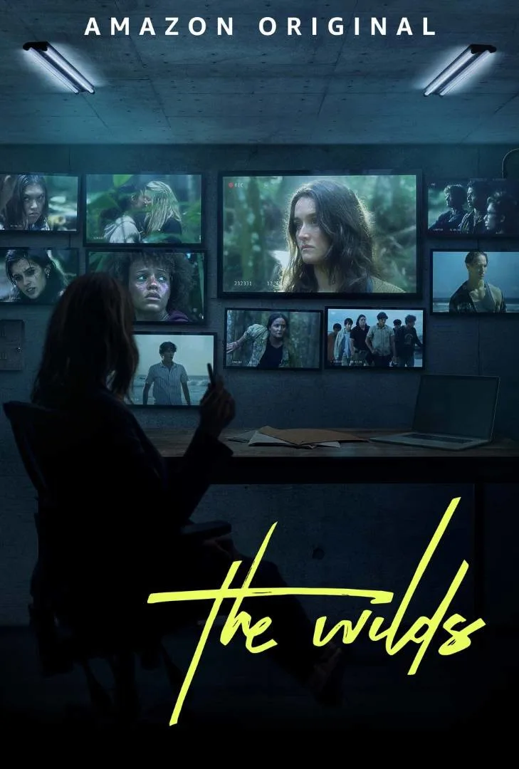 A person sits in a dark room, facing a wall of screens showing scenes of young women in the wilderness. The text reads "Amazon Original" at the top and "The Wilds" in yellow script at the bottom.