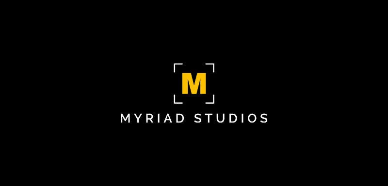 Logo for Myriad Studios with a bold yellow "M" surrounded by four white corner brackets on a black background. The words "MYRIAD STUDIOS" appear below in white, uppercase letters.