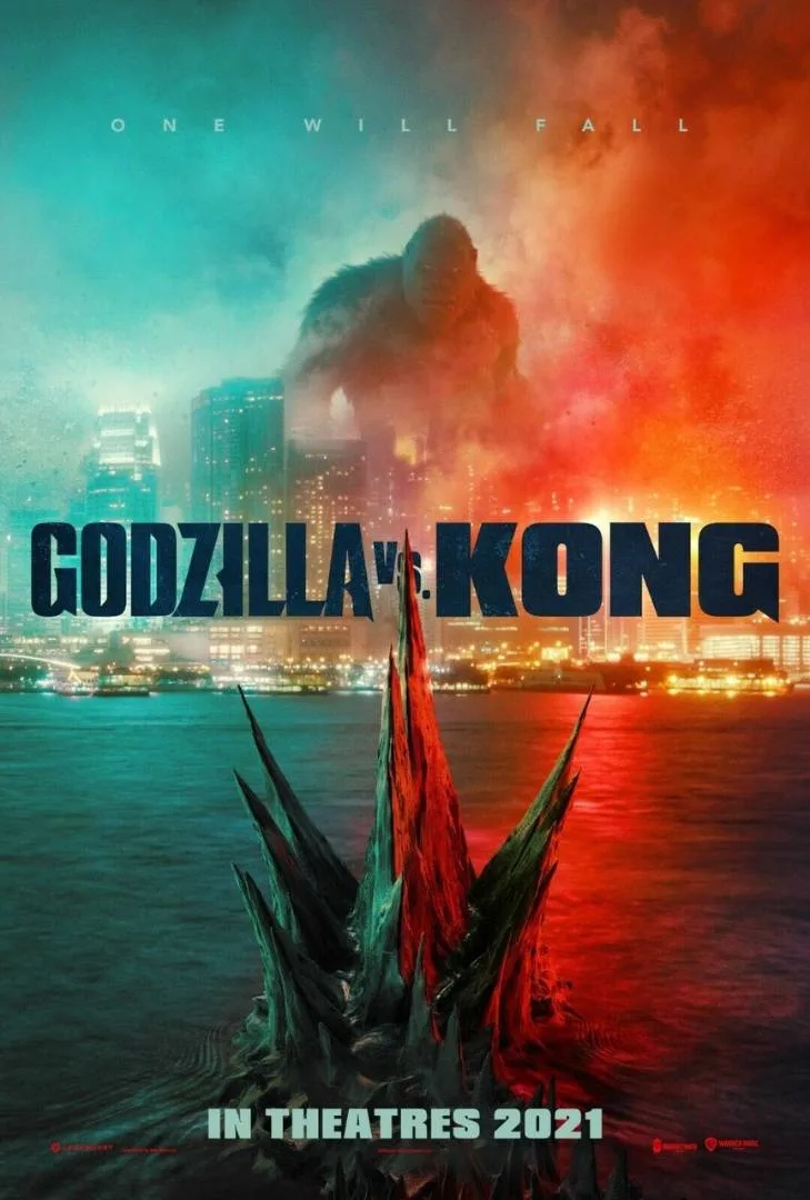 Movie poster for "Godzilla vs. Kong" showing Godzilla's spikes emerging from water in the foreground and a giant Kong towering over a city skyline, with the title and “In Theatres 2021” at the bottom.