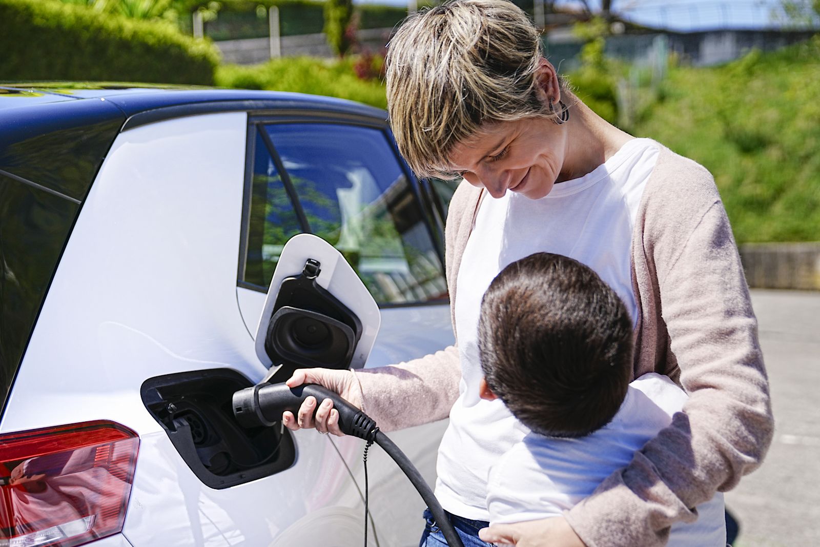 Woman and her child charging her EV
