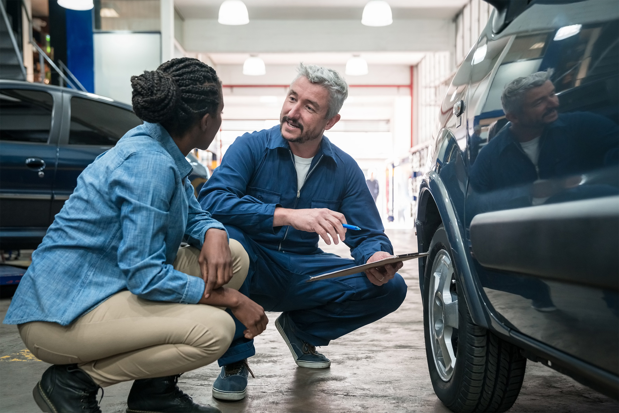 A mechanic and customer next to a car