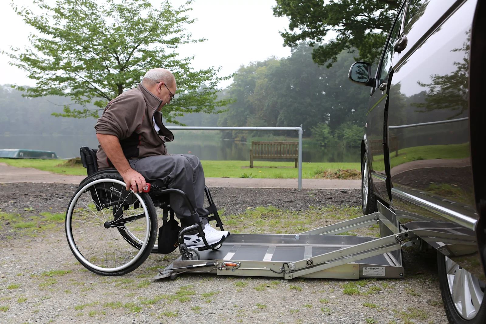A man in a wheelchair using a lift to get into a WAV