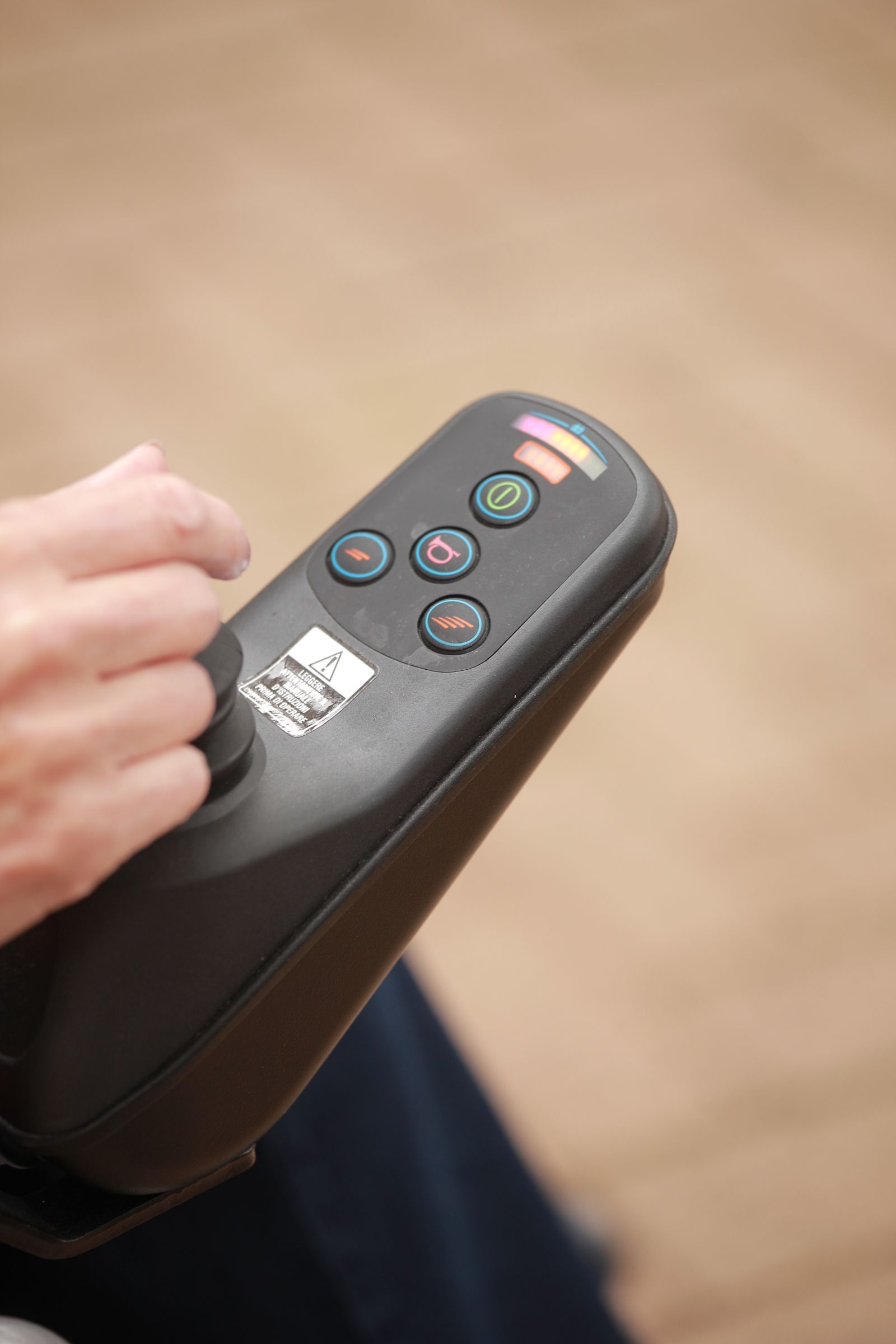A close-up of a hand using controls on a powered wheelchair
