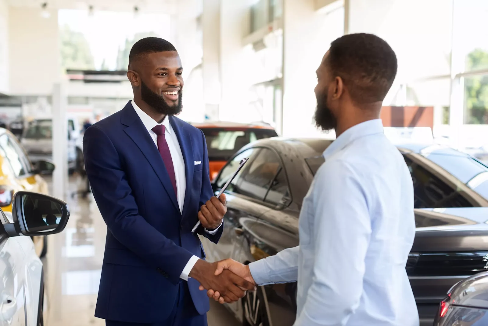 customer shaking hands with employee at car dealership