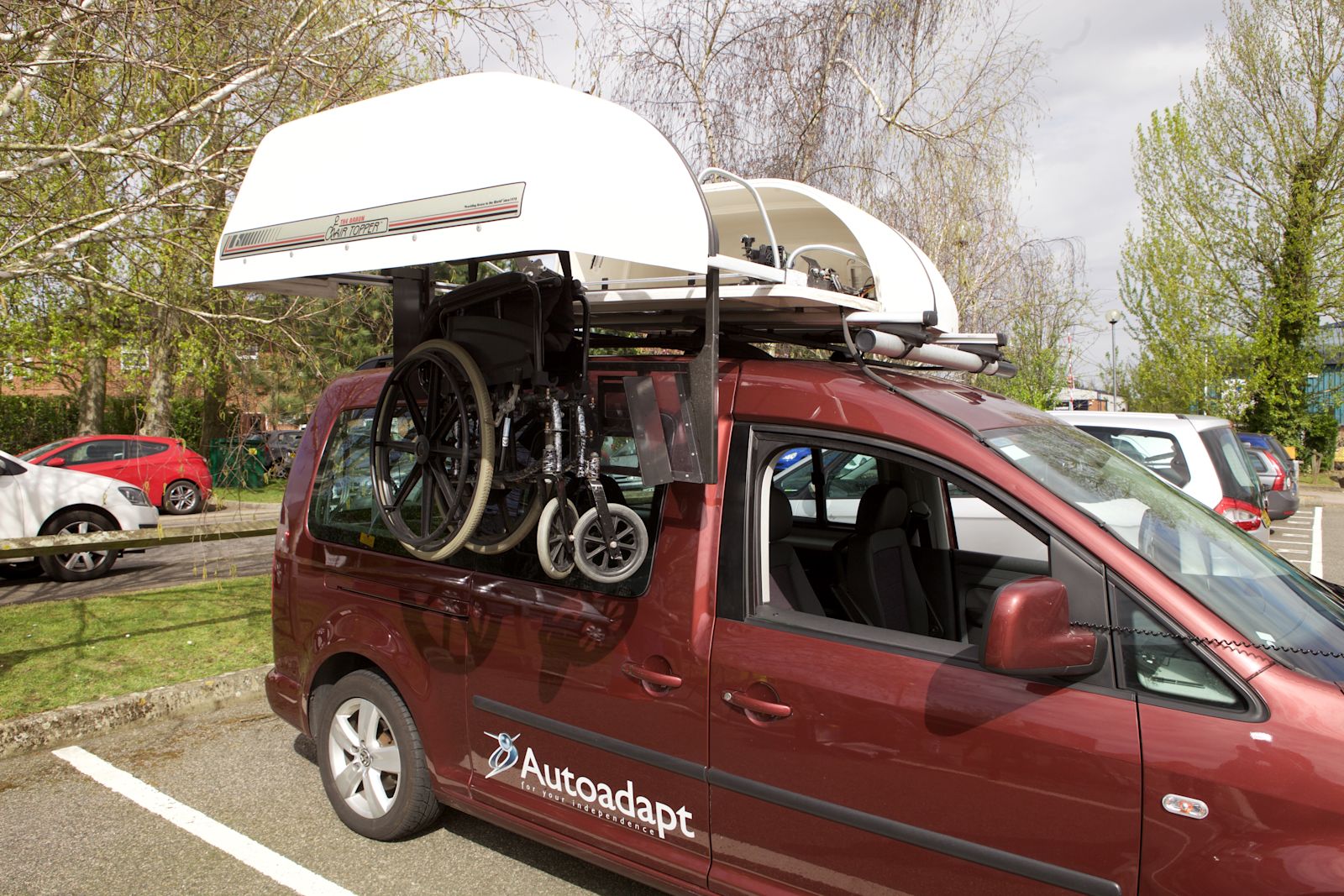 A rooftop stowage system on a car lifting a wheelchair