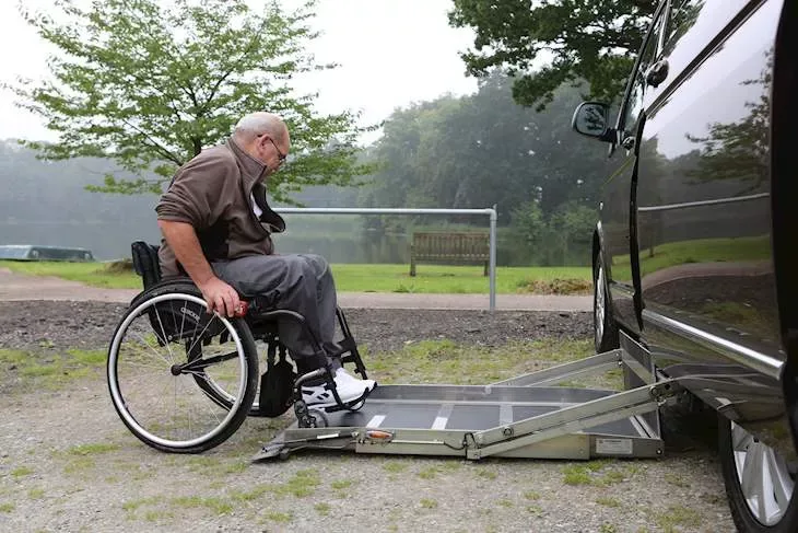 A man in a wheelchair using a lift to get into a WAV
