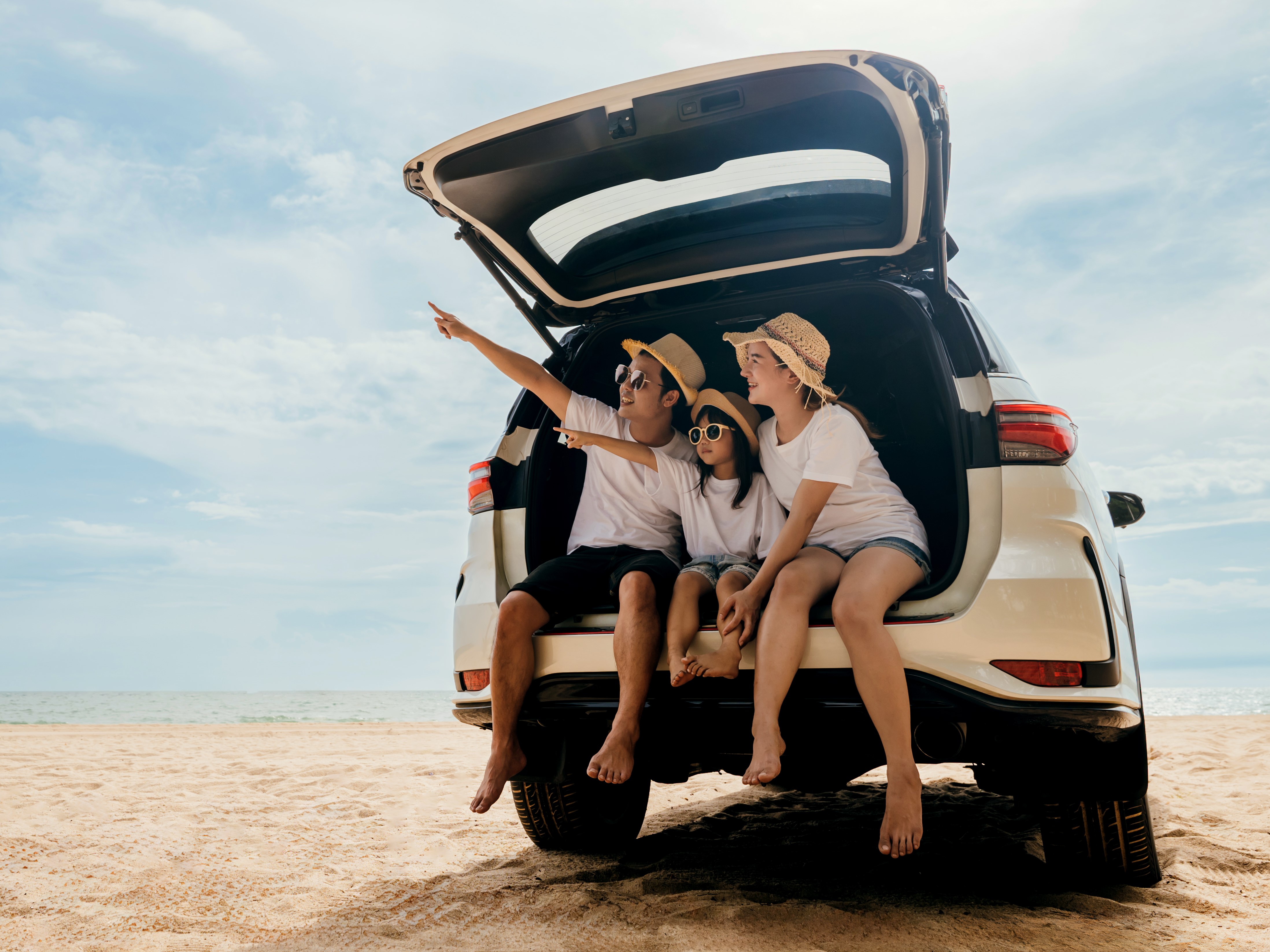 Family sitting in the trunk of a car at the beach