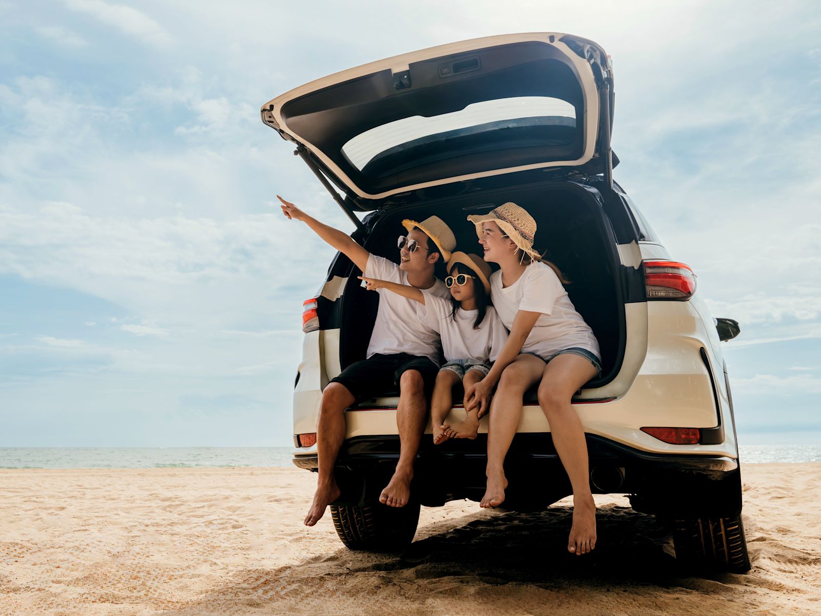 Family sitting in the trunk of a car at the beach