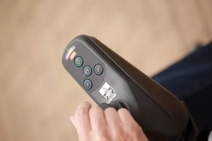 A close-up of a hand using controls on a powered wheelchair
