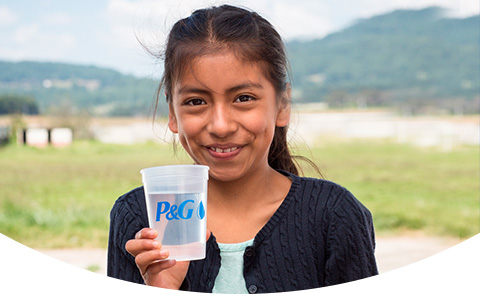 Smiling girl holding a glass of purified water with the P&G logo on the cup.