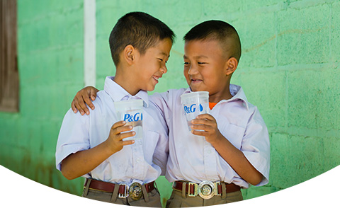 Two smiling children in white t-shirts holding glasses of purified water with the P&G logo