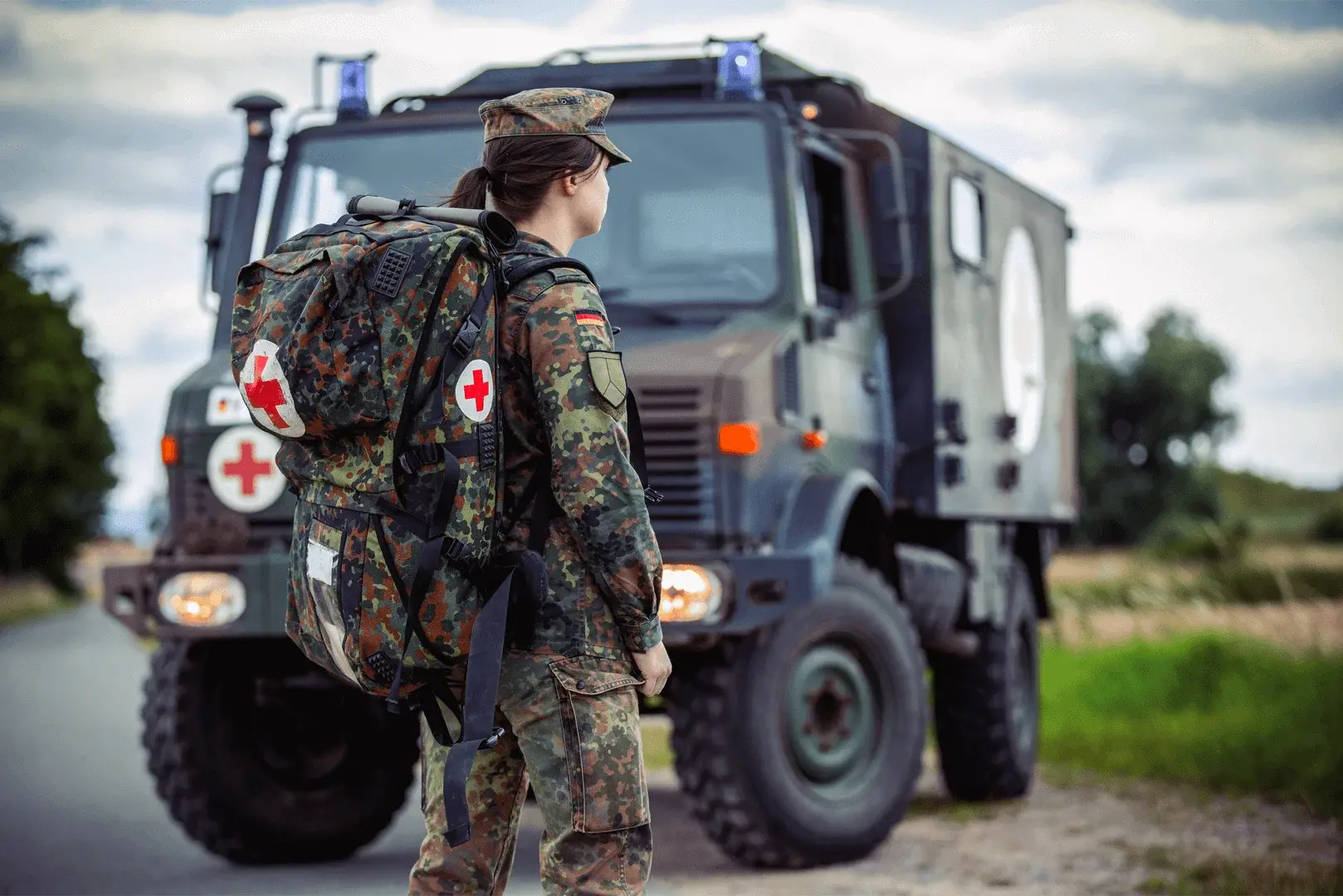 Foto: eine jugendliche Person steht in Bundeswehrdienst Uniform vor einem Sanitäter PKW