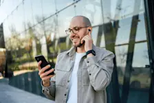 Foto: Ein Mann telefoniert über seine Kopfhörer die per Bluetooth mit dem Handy verbunden sind.