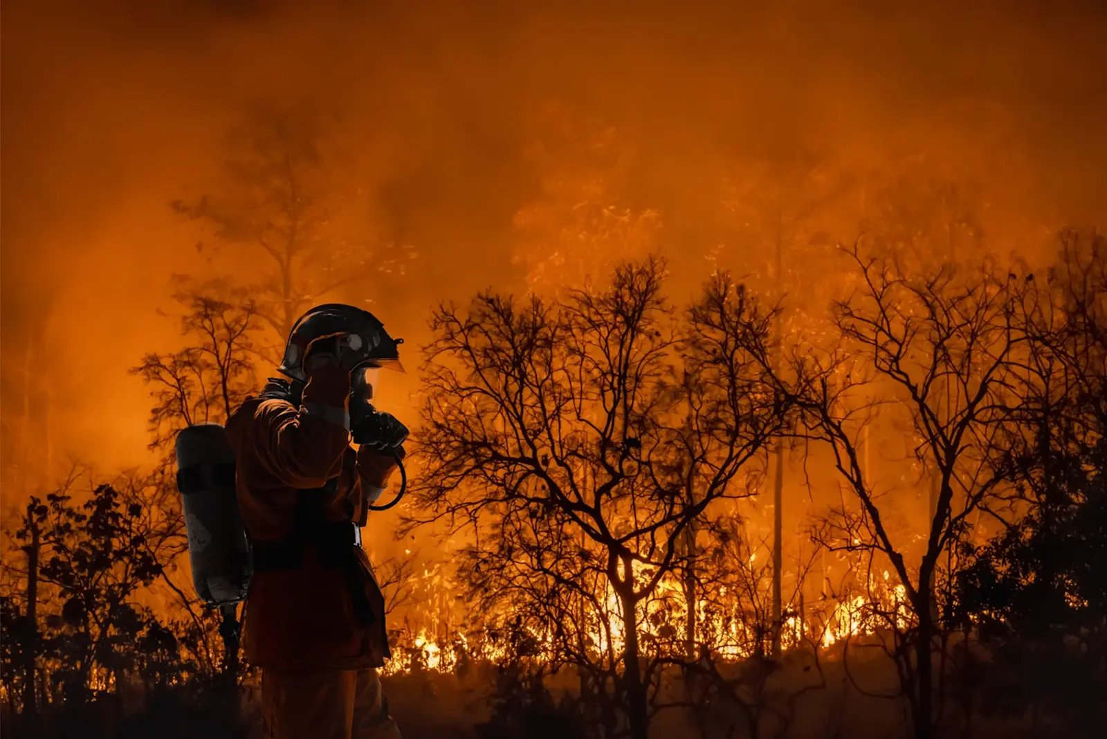 Ein Feuerwehrmann steht im Schatten der Flammen.