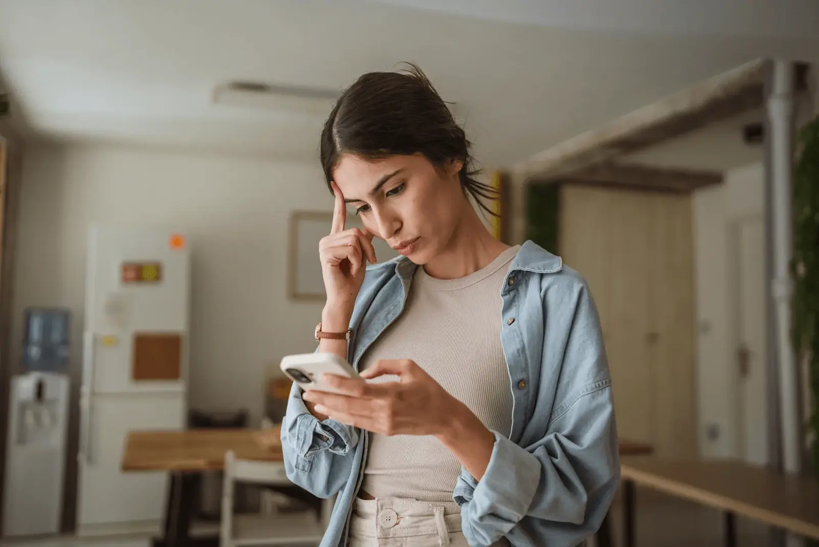 Foto: Eine Frau schaut nachdenklich auf ihr Handy. Instagram schaltet die Ende-zu-Ende-Verschlüsselung für Einzelchats ab. 
