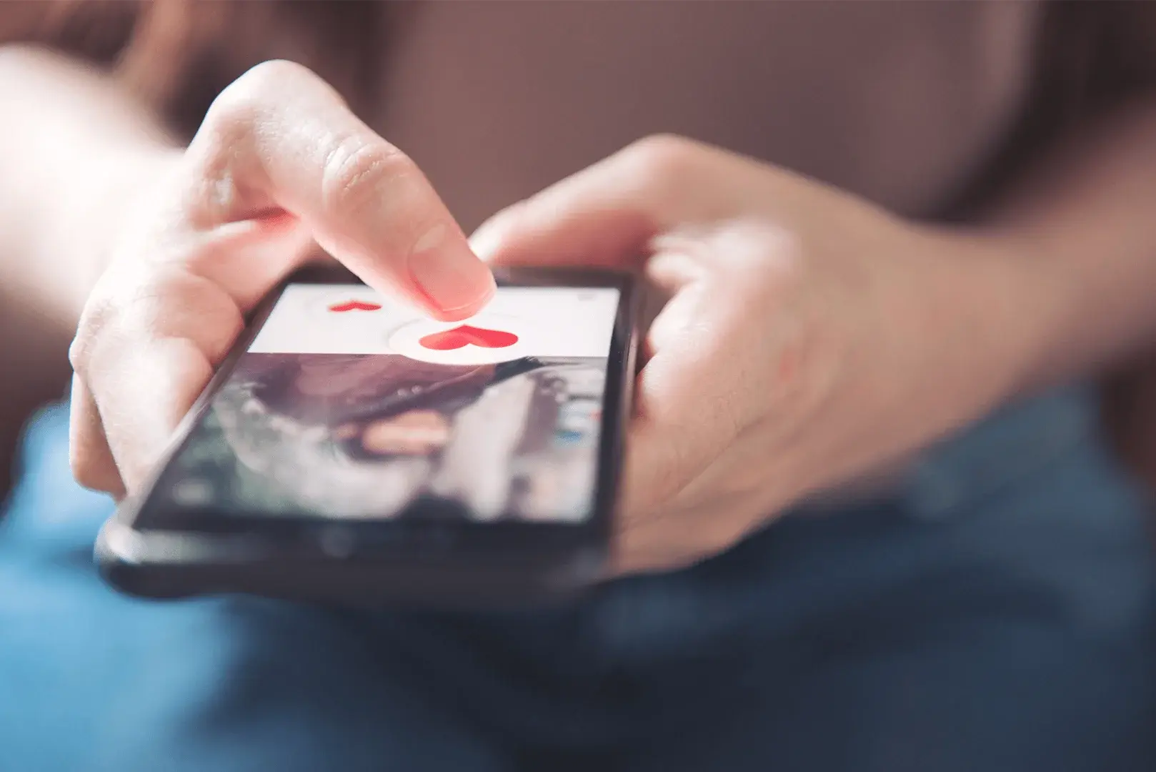 Foto: eine Person hält ein Smartphone in der Hand und hat eine Dating-App geöffnet.
