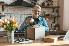 Foto: Ein Mann sitzt in der Küche und packt sein Paket ein, das er privat verkauft.