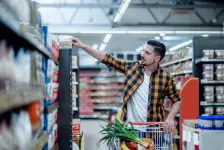 Mann wählt Lebensmittel im Supermarkt aus und schaut auf die Regale. 