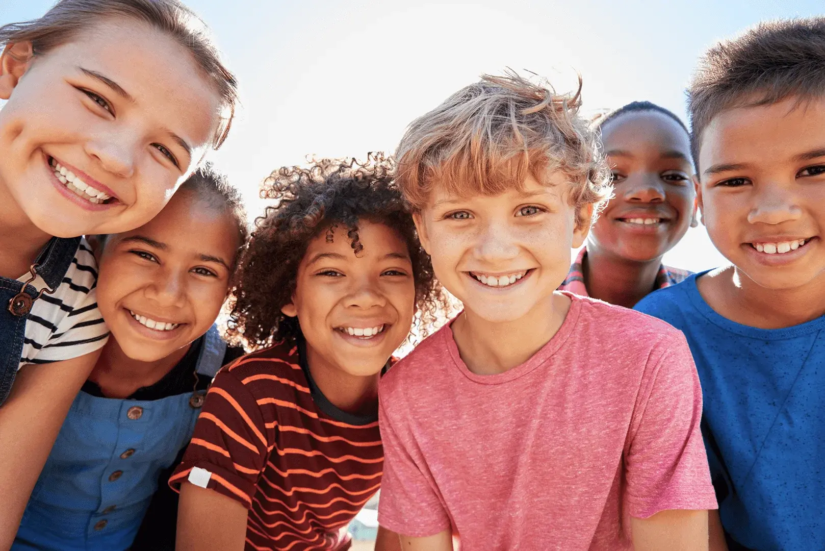 Foto: Eine Gruppe Kinder lächelt glücklich in die Kamera.