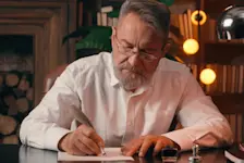 Foto: ein älterer Herr sitzt an seinem Schreibtisch und verfasst sein Testament.
