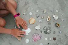 Foto: ein Kind zeigt die gesammelten Muscheln, Korallen und anderes Strandgut