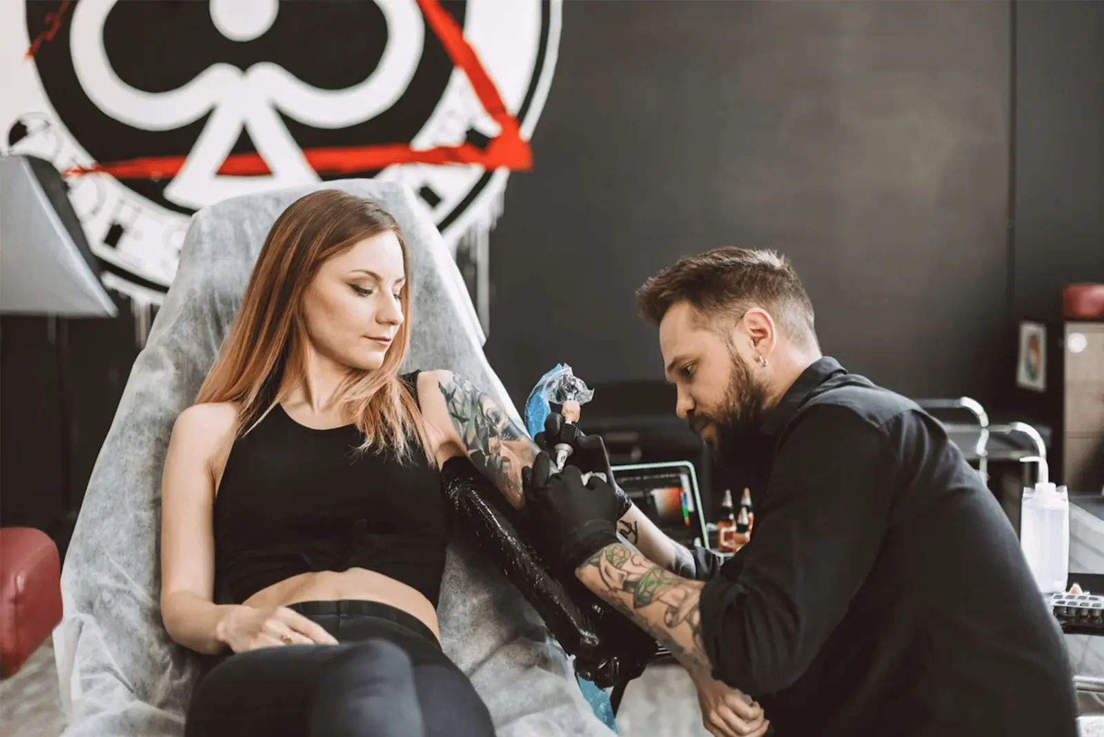 Ein Mann tätowiert einen Arm einer Frau in einem Tattoo-Studio.