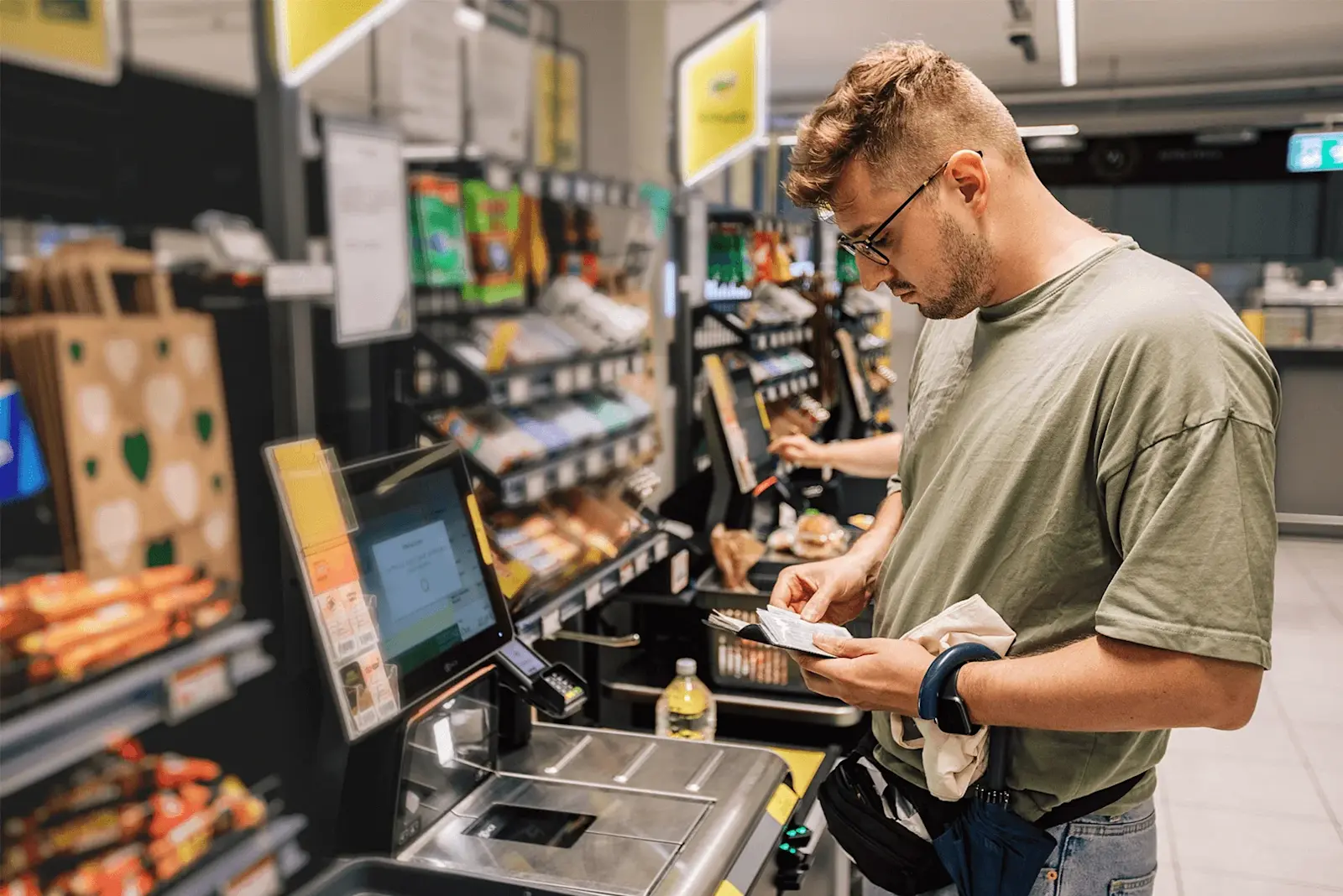 Ein Mann schaut auf den Kassenbeleg an der SB-Kasse im Supermarkt.