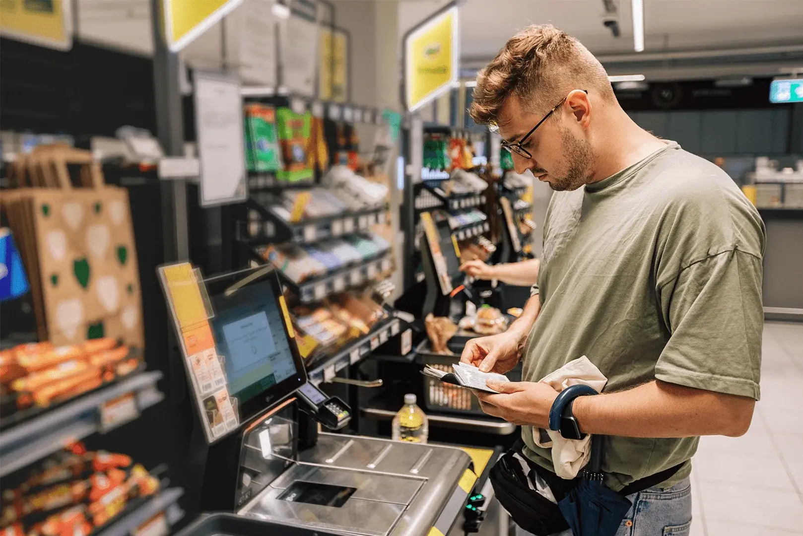 Ein Mann schaut auf den Kassenbeleg an der SB-Kasse im Supermarkt.