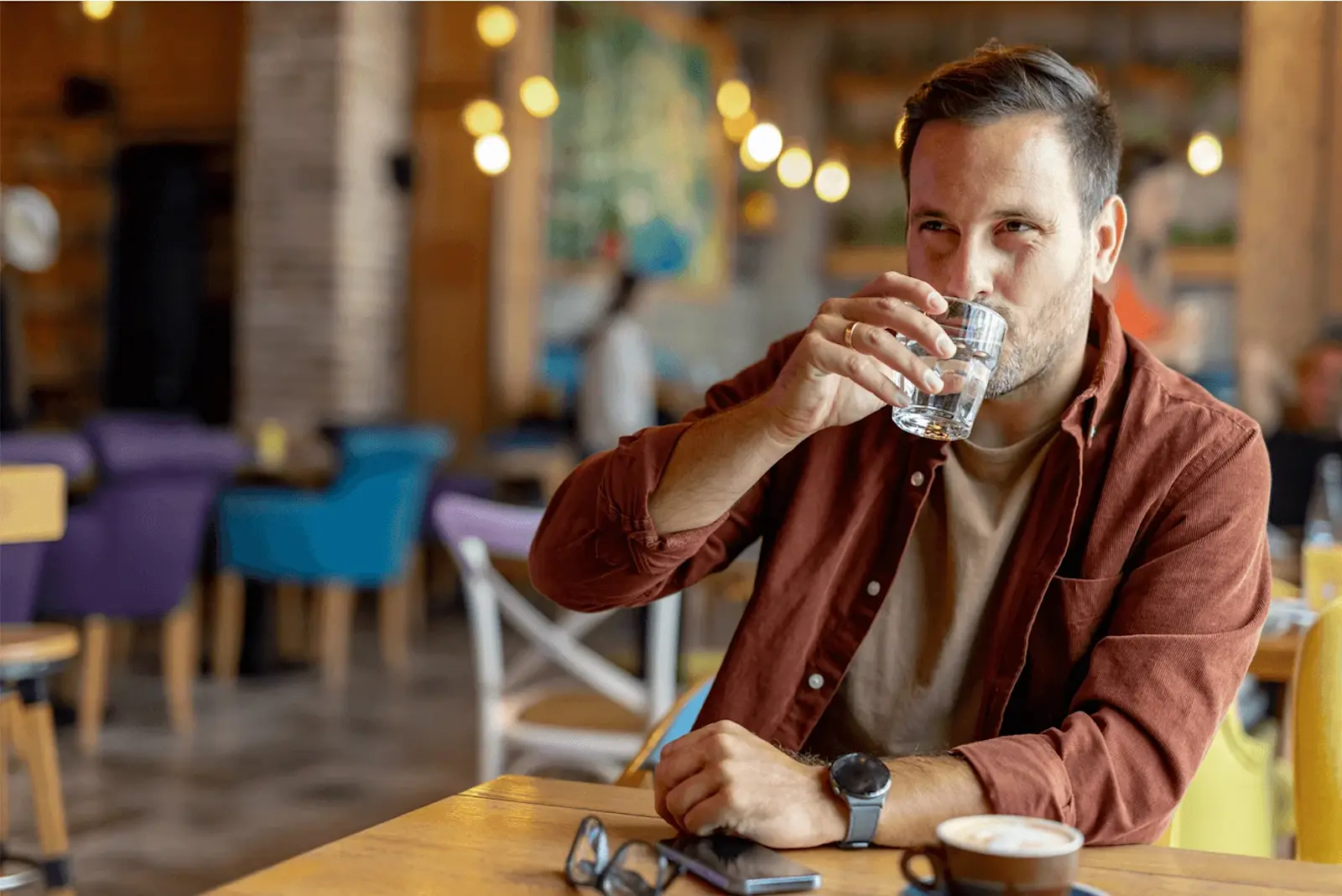 Foto: ein Mann sitzt in einem Restaurant und trinkt aus einem Glas Wasser