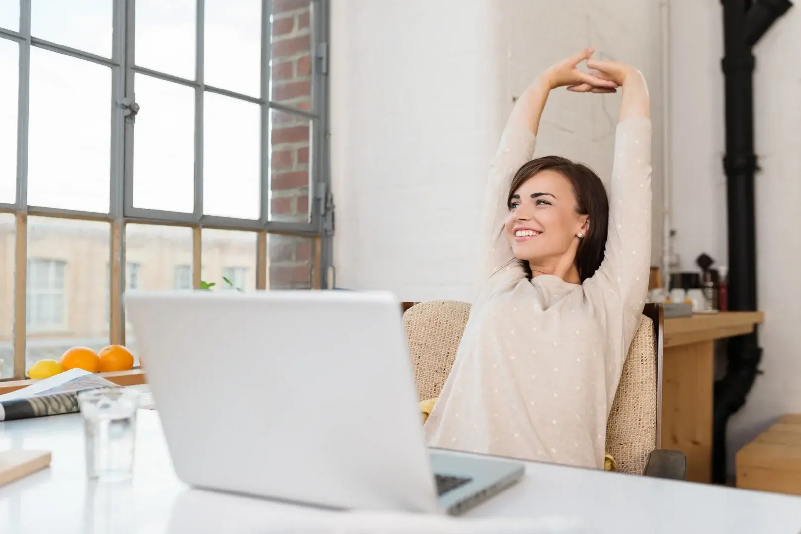 Eine Frau entspannt sich vor ihrem Laptop nach dem Prinzip des Bare Minimum Monday