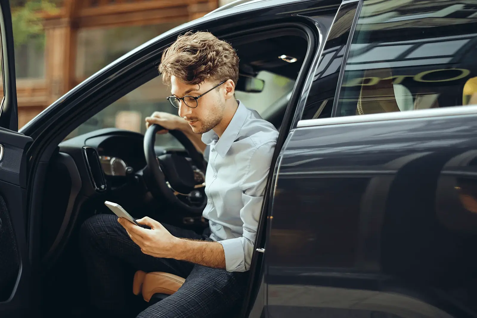 Foto: ein junger Mann steigt ins Auto und öffnet die i-Kfz-App der Bundesregierung für den digitalen Fahrzeugschein